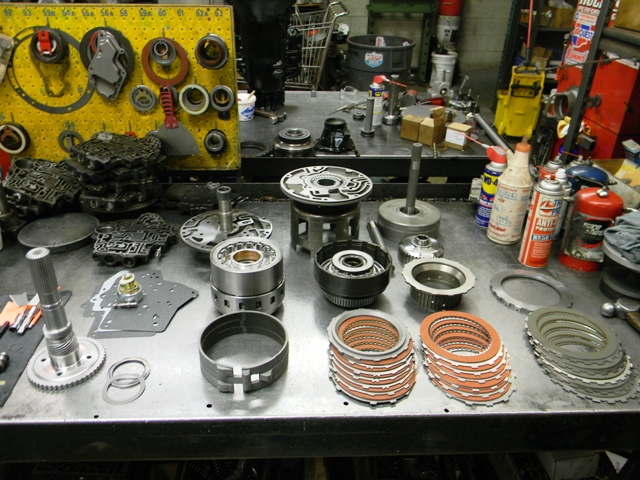 Here's an exploded view of al of the components that make up a Hughes Turbo 400 build. From left to right, top to bottom are: valve body, output shaft, pump stator, planetary gear sets, rear band, pump body and gears, direct drum, direct clutch pack, forward drum and input shaft, forward clutch hub, direct clutch hub, direct clutch pack, intermediate pressure plate, intermediate clutch pack. 