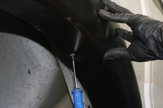 The factory screws holding up the fender well are removed to make way for the fender flare's inner piece.