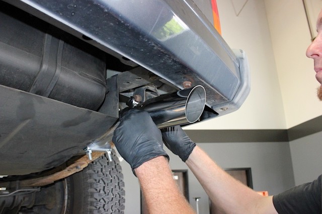 Top left: A mark is made for a cut to fit the exhaust tip. Top middle: After the cut is made, the metal on the tailpipe is deburred. Top right: The tailpipe is inserted up and over the axle. Bottom: The exhaust tip is fitted to the tailpipe and tightened.