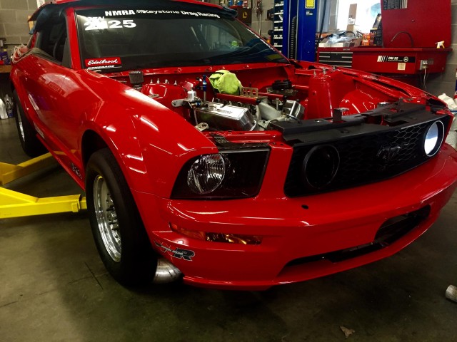 The AFR-equipped, small block Ford being lowered back into it's home after some routine maintenance in Valerie's sleek red Ford Mustang.