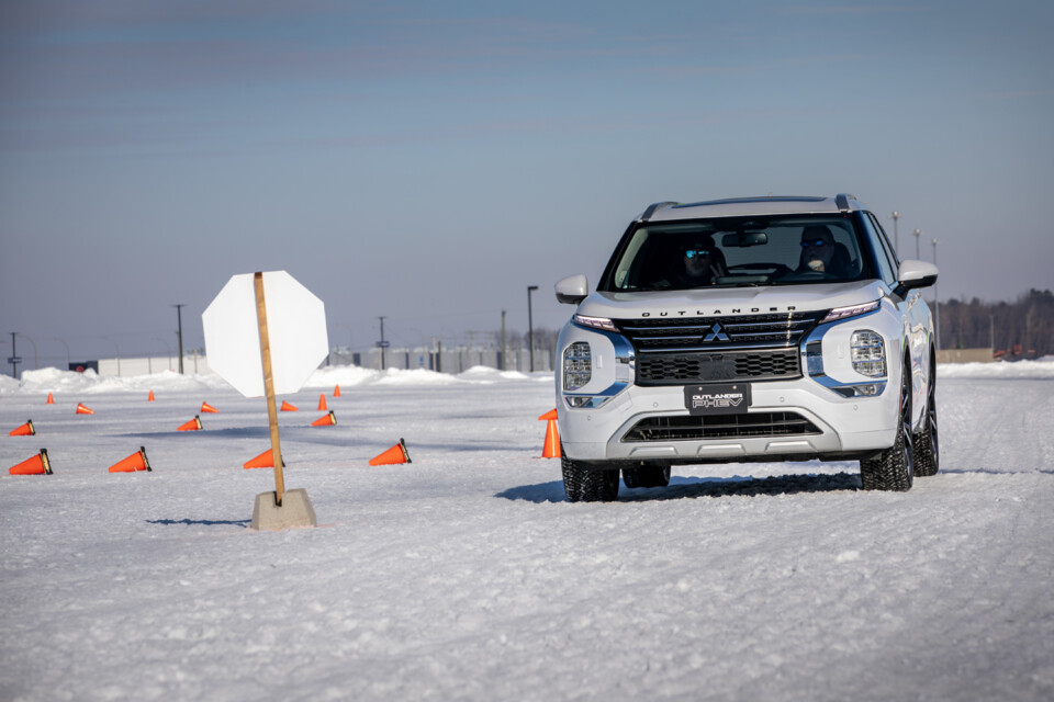 White 2024 Mitsubishi Outlander PHEV stopped at stop sign on snow and ice track.