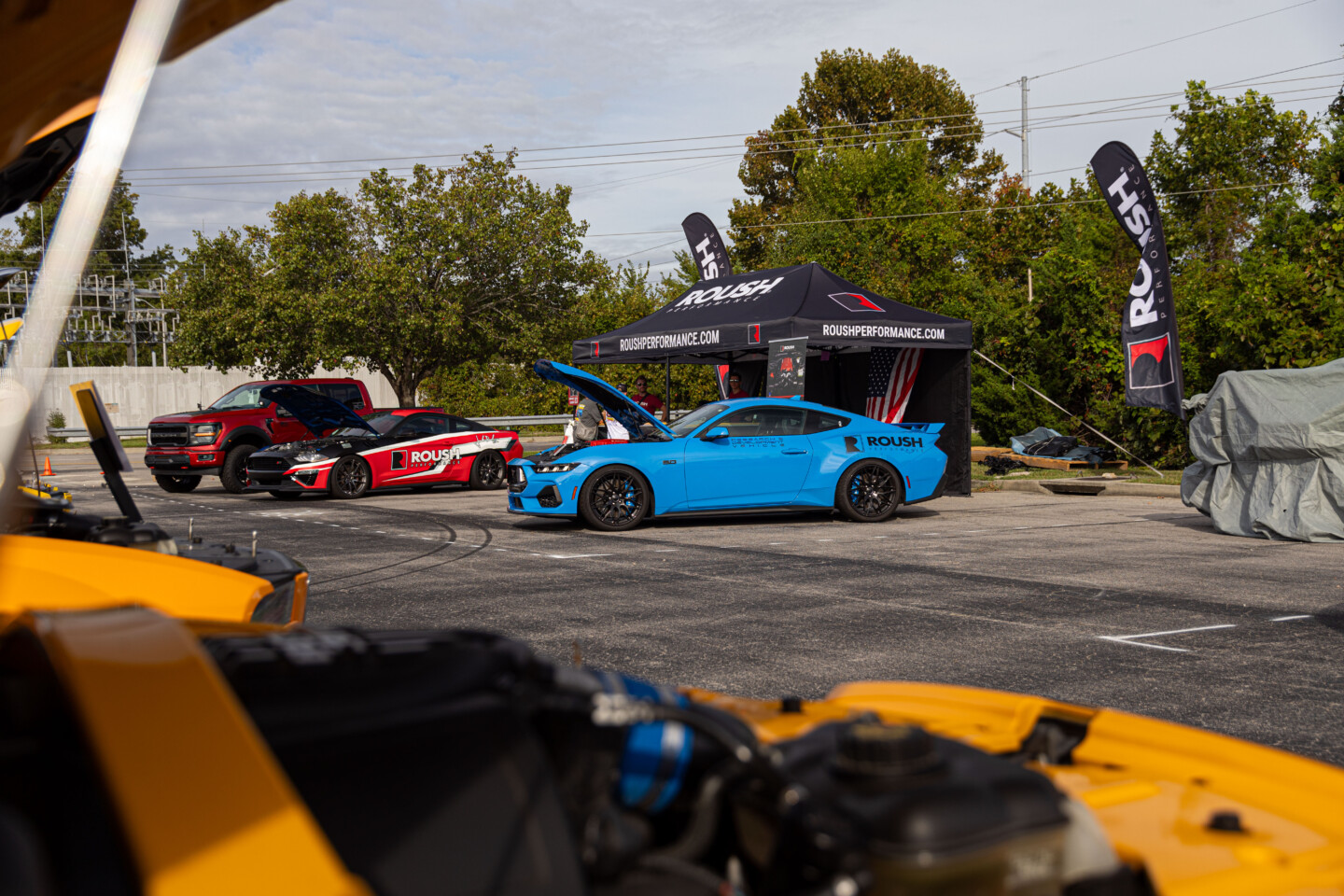 ROUSH Performance display at Mustang Week Car Show 2024. Images shot from behind engine bay of an orange Mustang.