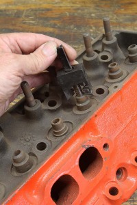 Production cylinder head valve guides are often both too large and too tall. Comp offers arbors and cutters that you can use to reduce both the outside diameter and the height while also cutting the guide for a performance Viton style seal. These tools are especially useful when modifying a production small-block Chevy head. Note that the guide in the foreground has already been cut.